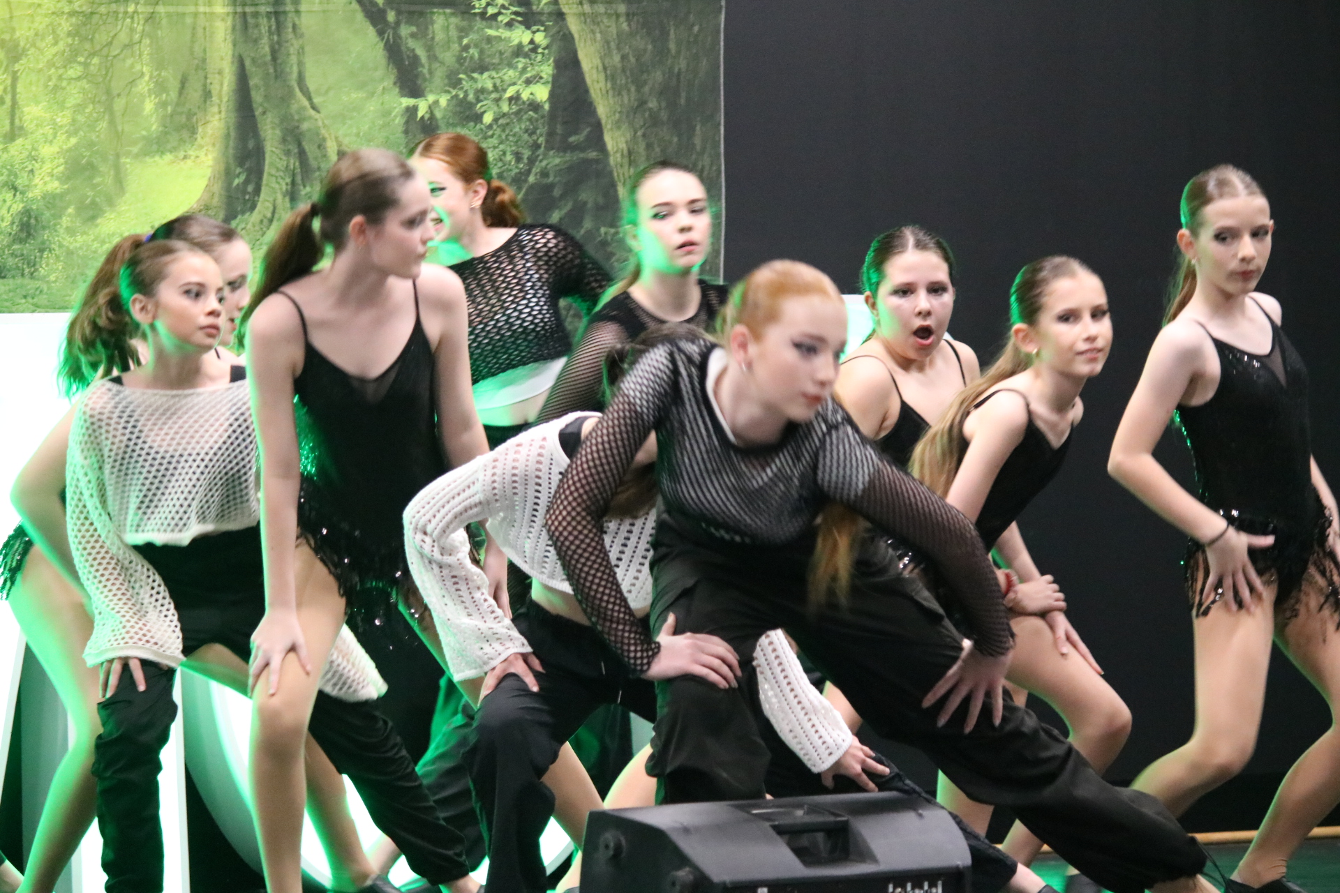 Group of performers on stage wearing coordinated outfits and moving in a dance formation
