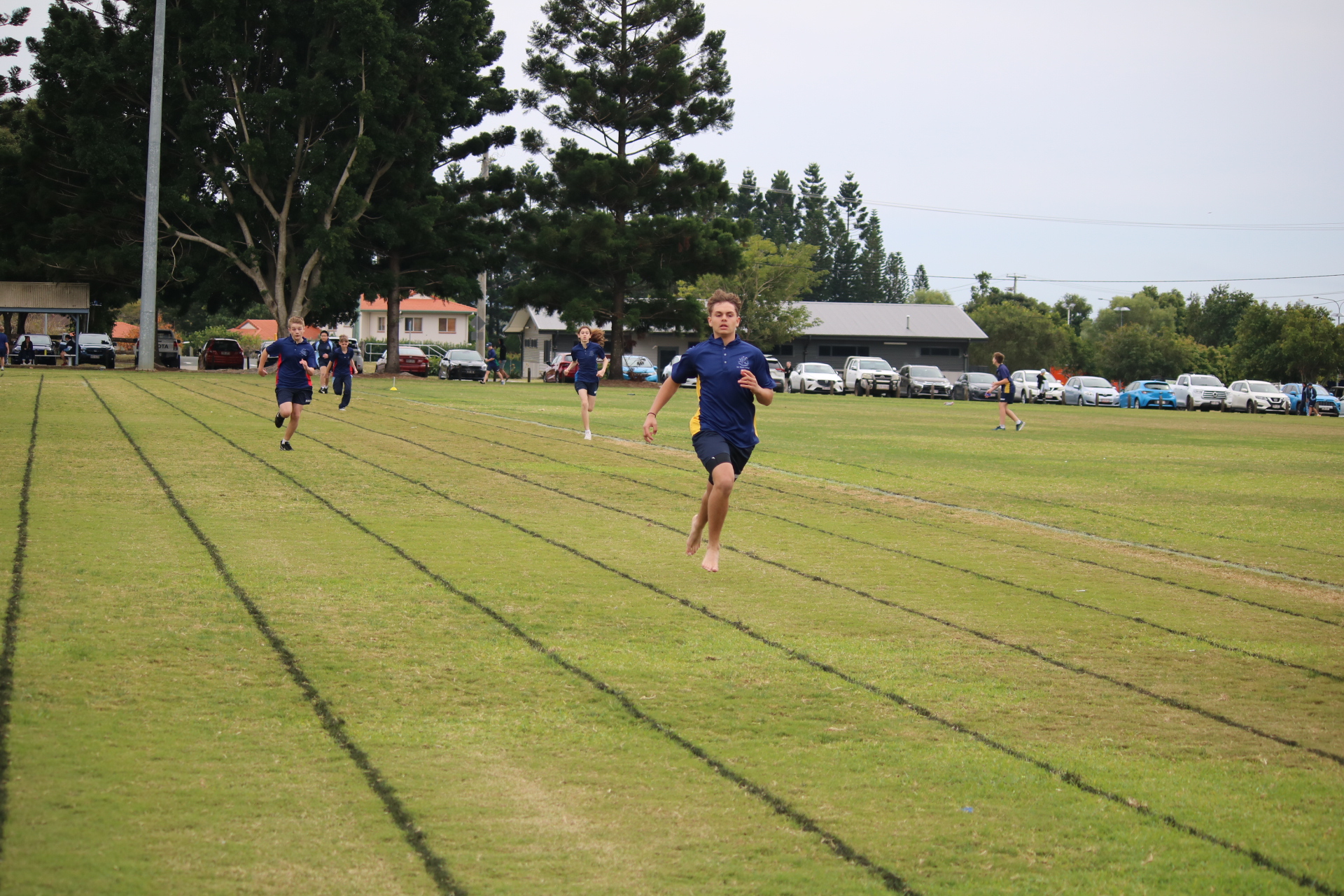 Students running on a marked grass track during an outdoor race